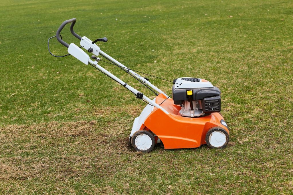 Orange motordriven gräsmaskin som står parkerad på en gräsmatta