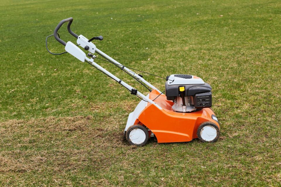 Orange motordriven gräsmaskin som står parkerad på en gräsmatta