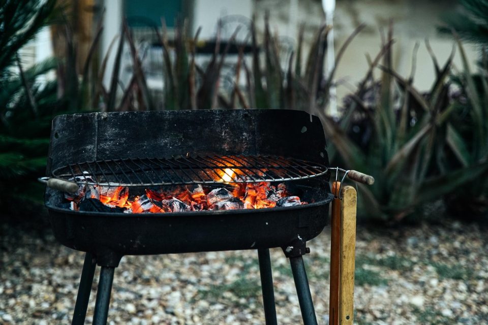 Kolgrill med glödande kol under gallret på en grusgång